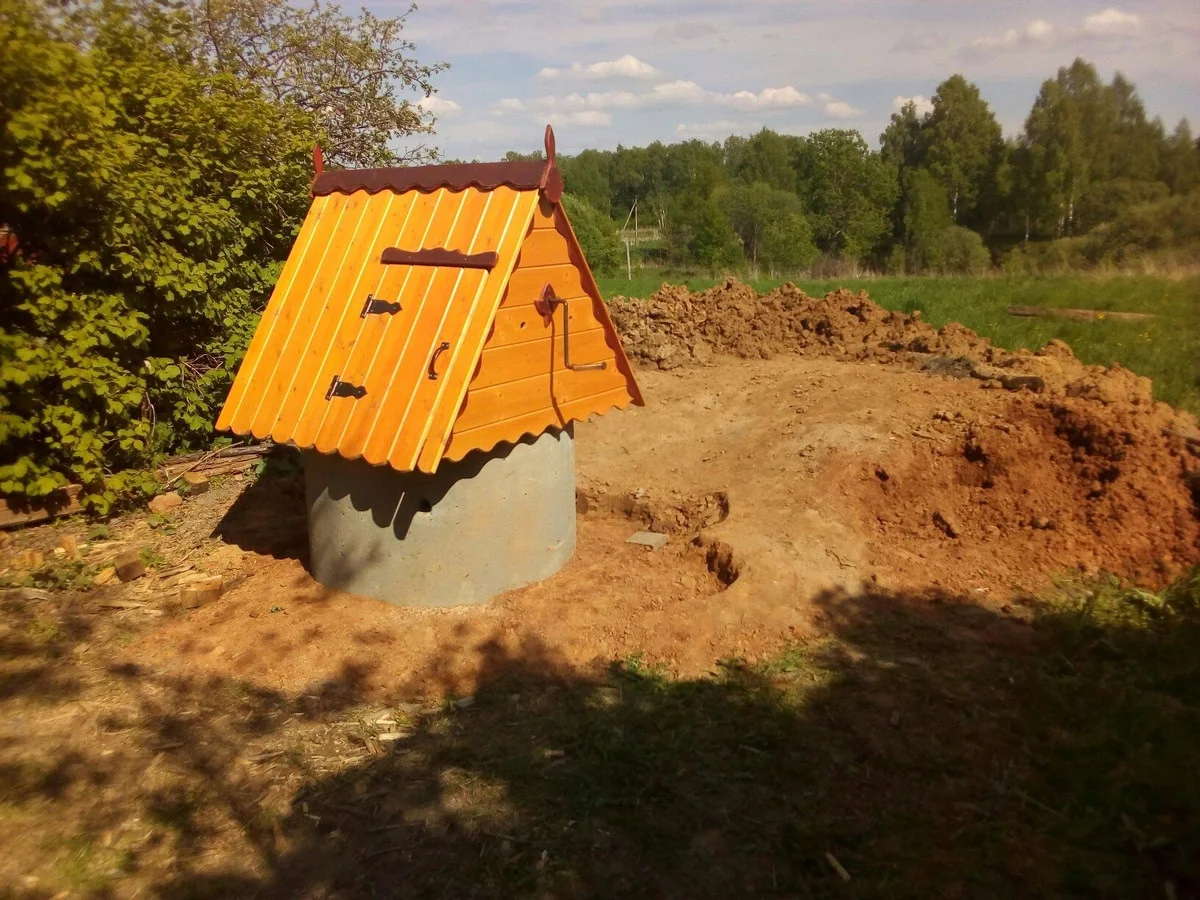 Новый колодец с оранжевым домиком, вокруг свежий грунт